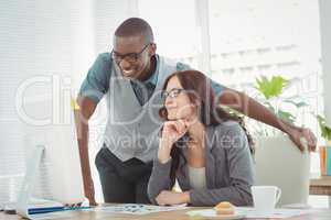 Smiling business professionals looking at computer while working