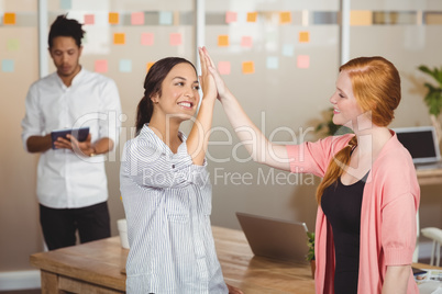 Happy businesswomen giving high five in office