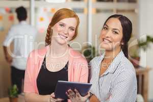 Portrait of happy businesswomen using digital tablet in office
