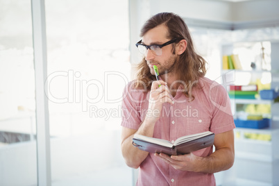 Thoughtful hipster holding pen and book
