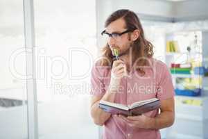 Thoughtful hipster holding pen and book