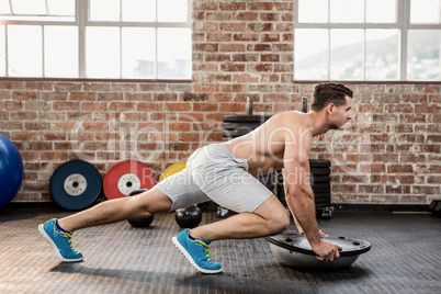 Shirtless man doing exercise with bosu