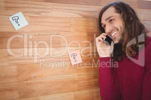 Happy man using mobile phone leaning on wooden wall