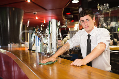 Confident male bartender cleaning bar counter