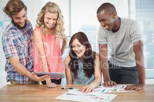 Happy man showing digital tablet to coworkers