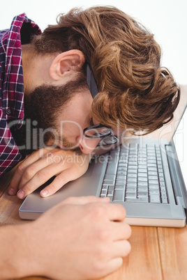 Close-up of hipster napping with head on laptop
