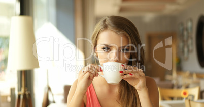 Young Woman Drinking Coffee in Sunny Cafe