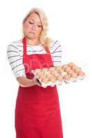Hausfrau in Schürze hält eine Palette Eier und zieht eine Schnute