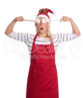 Frau mit Weihnachtsmütze hält Kochlöffel und ist erstaunt