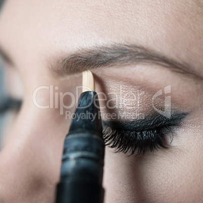 Close Up of Woman Applying Make Up Along Brow Line
