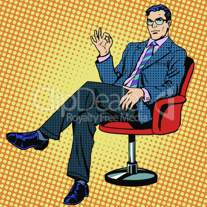 Businessman sitting in an armchair gesture okay