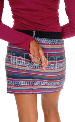 Woman in skirt from back, crossed finger.