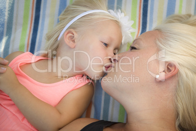 Little Girl Laying on Blanket Kisses Her Mommy