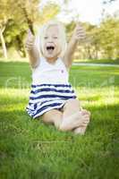 Cute Little Girl with Thumbs Up in the Grass