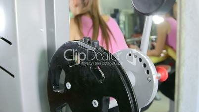 Young fit woman doing hamstrings exercise on leg curl machine in fitness club