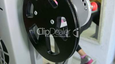 Young fit woman doing hamstrings exercise on leg curl machine in fitness club
