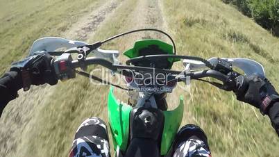 Point of View: Enduro biker riding motorcycle on dirt track