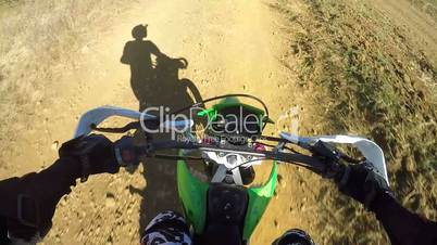 Point of View: Enduro rider in motorcycle protective gear riding bike on dirt track