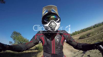 Point of View: Enduro rider in motorcycle protective gear riding bike on dirt track