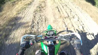 PoV: Enduro racer riding his offroad bike on dirt track climbing to the hill