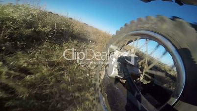 Enduro racer riding bike on dirt track jumping rear wheel point of view