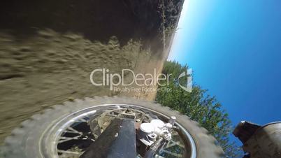 Enduro racer riding bike on dirt track kicking up dust rear wheel point of view