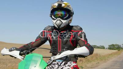 Motocross biker riding enduro motorcycle on country road