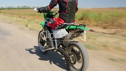 Motocross racer in motorcycle protective gear riding enduro bike