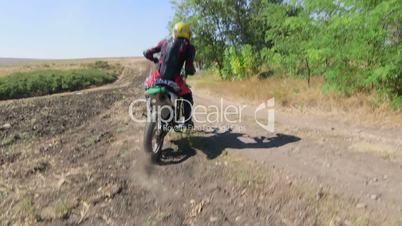 Enduro racer in motorcycle protective gear riding bike on dirt track