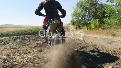Motocross racer start riding his dirt bike kicking up dust