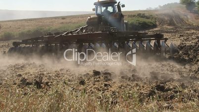 Modern tractor with harrows harrowing field