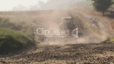 Modern tractor with harrows harrowing field