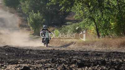 Enduro racer riding motorcycle on dirt track kicking up dust