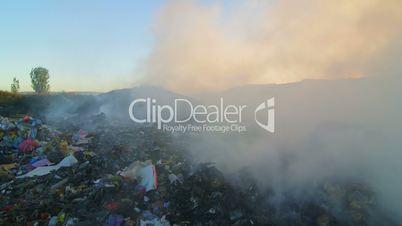 Burning garbage toxic smoke rises into the air pan shot