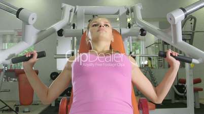 Young woman working out on chest press machine in health fitness center