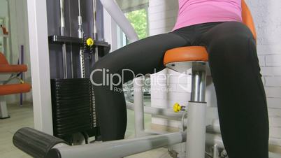 Young woman working out on weight exercise machine in health fitness club