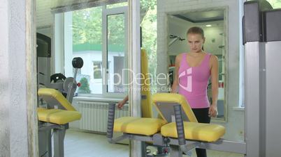 Young woman training on standing leg curl machine in health fitness club
