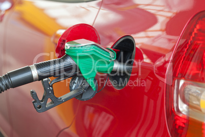 Red car at gas station being filled with fuel