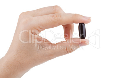 Woman's hand holding black pill