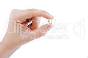 Woman's hand holding transparent yellow pill