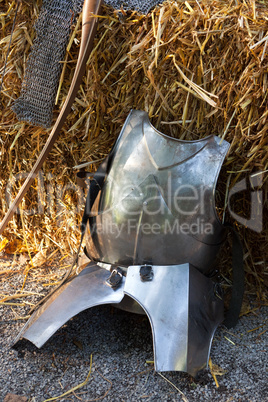 A silver metal armor lying in straw at a knight festival