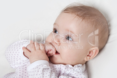 Cute baby girl chewing on her hand