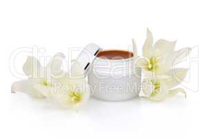 Open jar with the cosmetic cream and flowers isolated on white