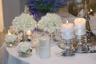 Table decorated with candles, hydrangeas and white roses