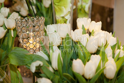 Crystal candle holder surrounded by white tulips