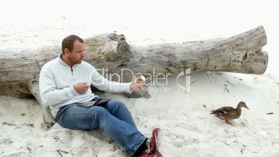 a man sitting in the sand on a fallen tree