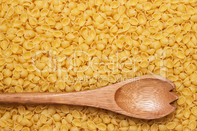 wooden spoon on uncooked macaroni background