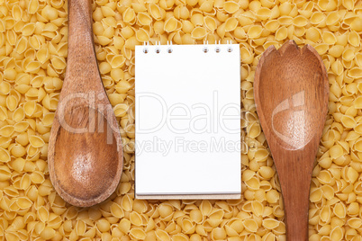 wooden spoons on uncooked macaroni background