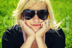 young girl in sunglasses sitting on grass