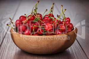 wooden bowl full of cherries on table